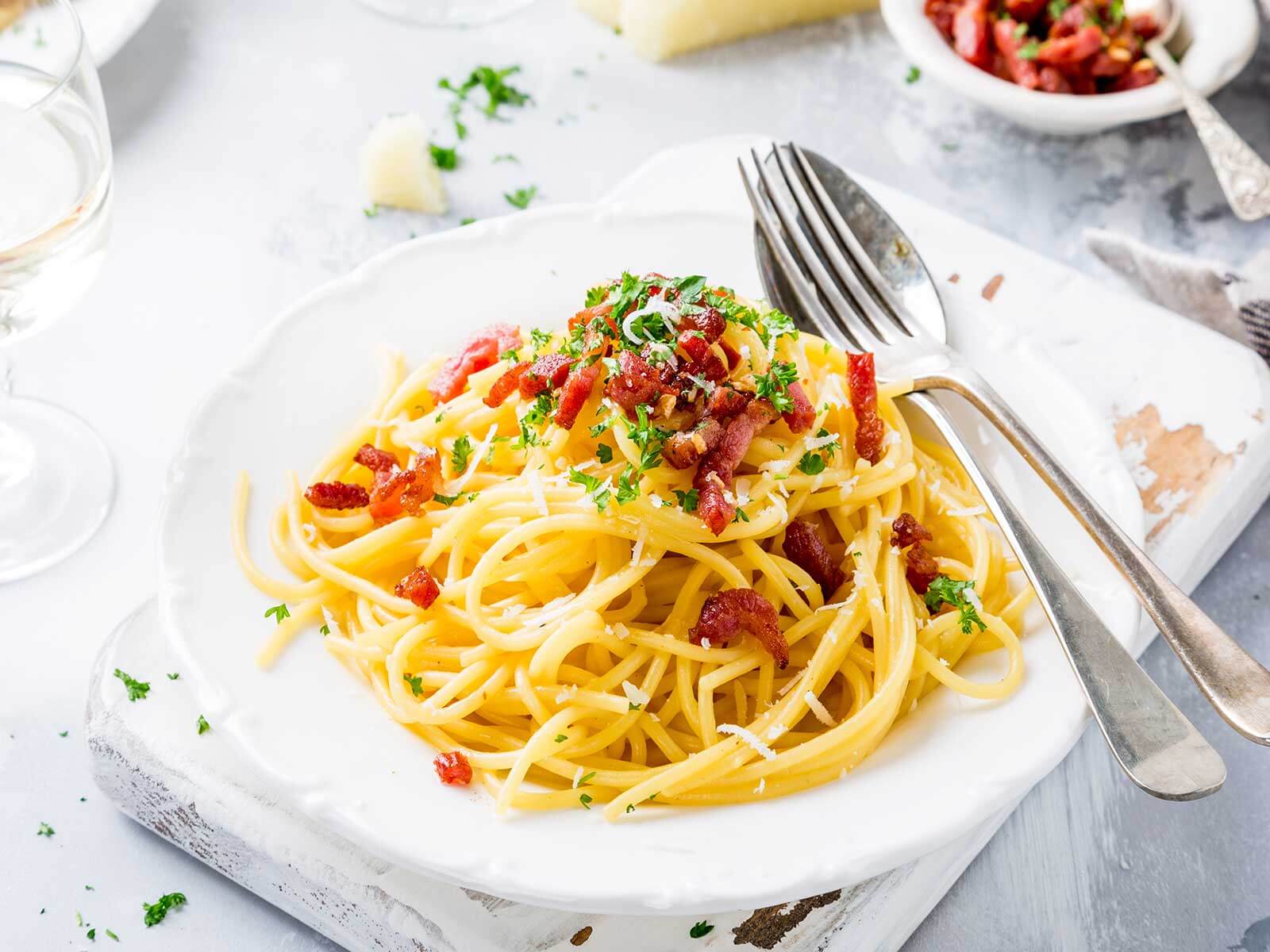 Spaghetti-Gericht von Tress mit gebratenen Speckwürfeln auf einem weißen Teller