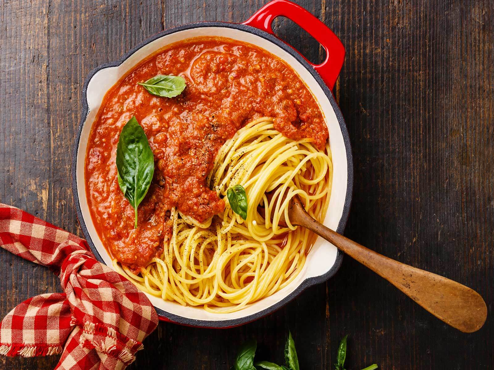 Ein roter Bräter mit Spaghetti und Tomatensoße mit Hackfleisch nach einem Rezept von Tress