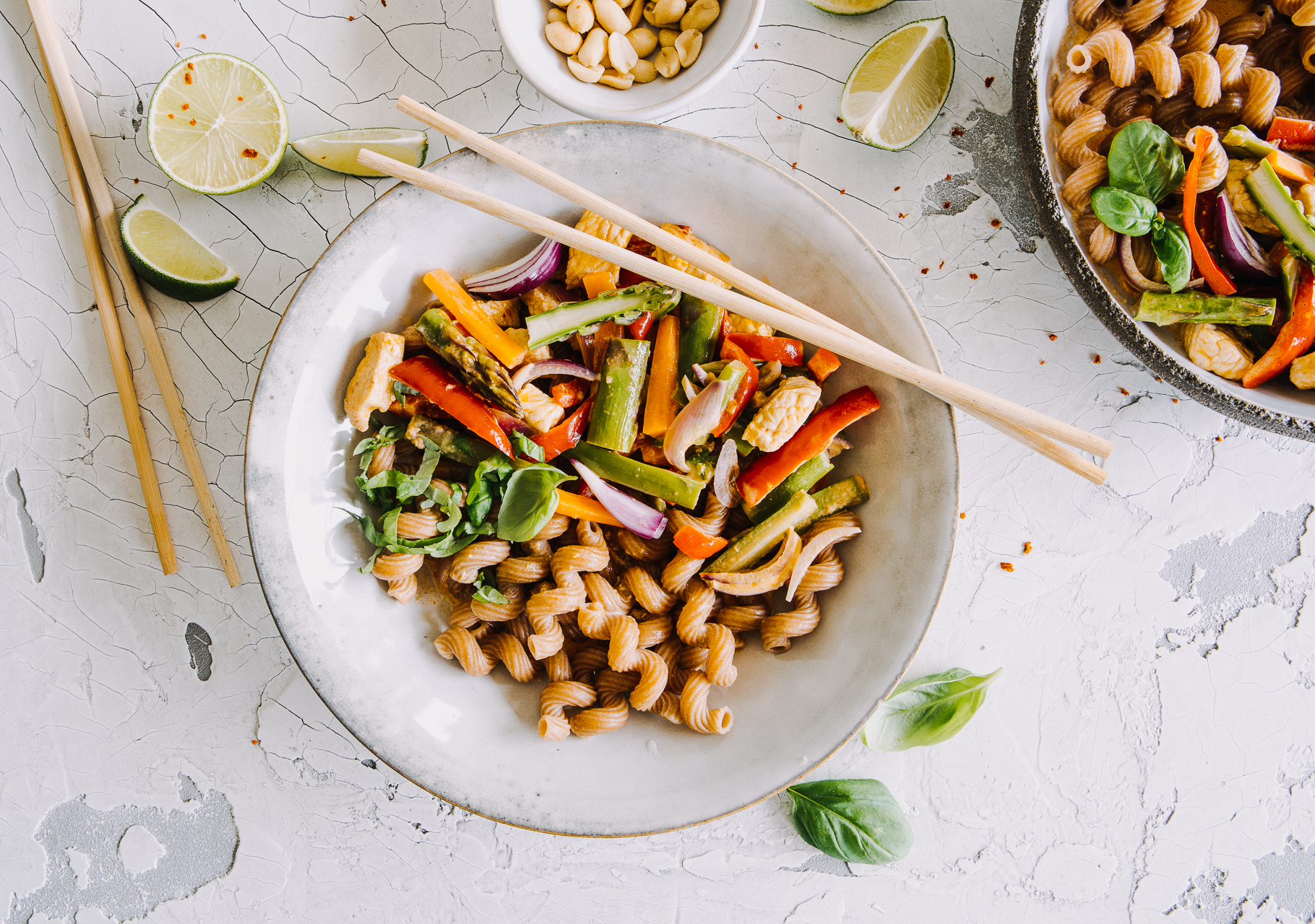 Asiatisches Curry-Gericht mit Putenstreifen, gebratenem Gemüse und Limette nach einem Rezept von Tress. Serviert in einer Schale mit Essstäbchen aus Holz.